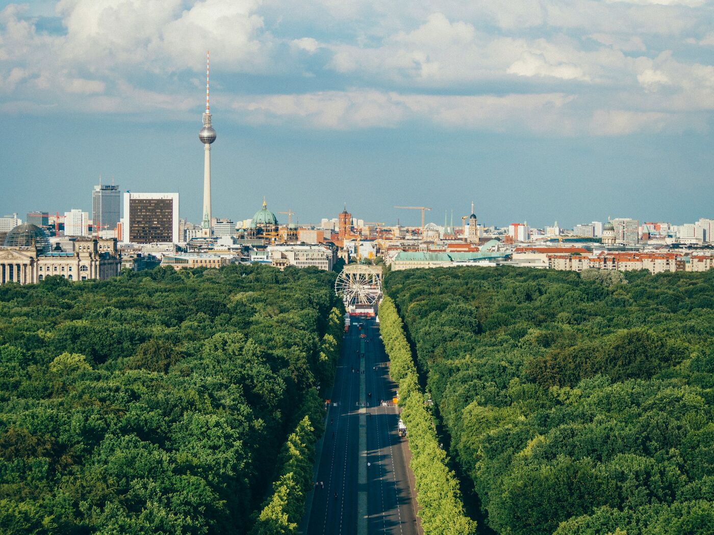 Blick über den grünen Tiergarten und die Straße des 17. Juni auf die Berliner Skyline mit Fernsehturm und Berliner Dom im Sommer