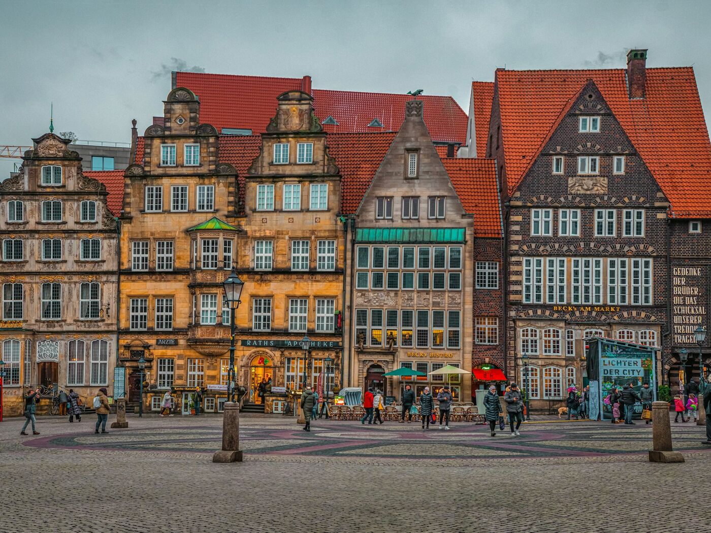 Historische Giebelhäuser am Bremer Marktplatz mit Raths-Apotheke und gepflastertem Platz unter winterlich bewölktem Himmel